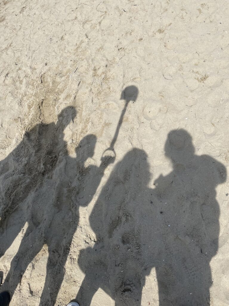 Familie foto van Guus van Zeijl en gezin op het strand met schaduwabeeldingen in het zand